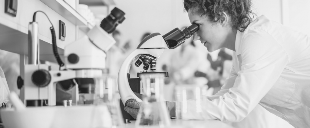ISO 15189 Header B&W A person looking through a microscope