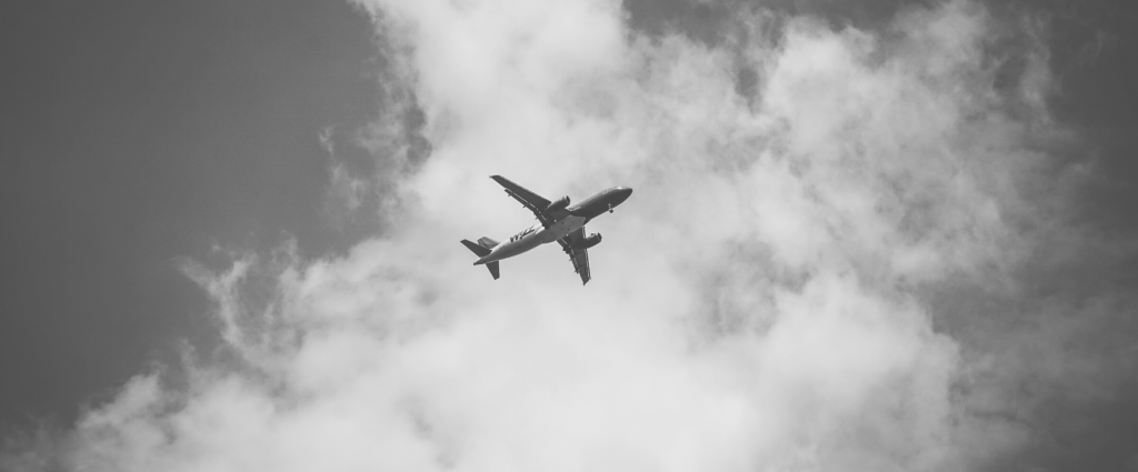 AS 9100 Header B&W An airplane flying in the sky